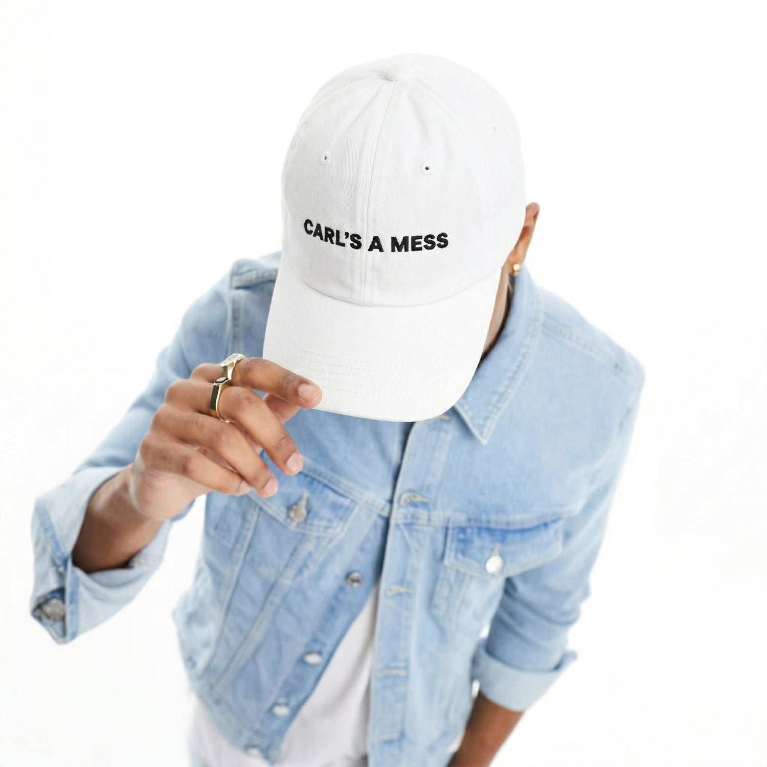 Person wearing a white cap with 'CARL'S A MESS' text, light blue denim jacket on a white background