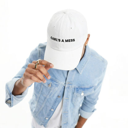 Person wearing a white cap with 'CARL'S A MESS' text, light blue denim jacket on a white background
