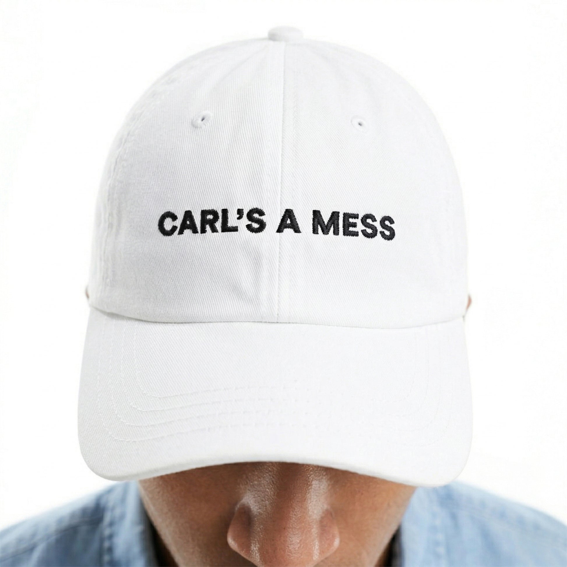 White cap with 'CARL'S A MESS' text worn by a person on a white background