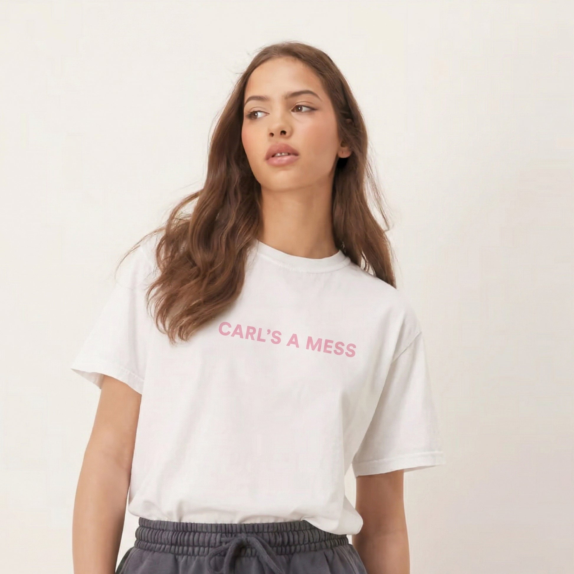 Woman wearing a white t-shirt with 'CARL'S A MESS' text on a plain background