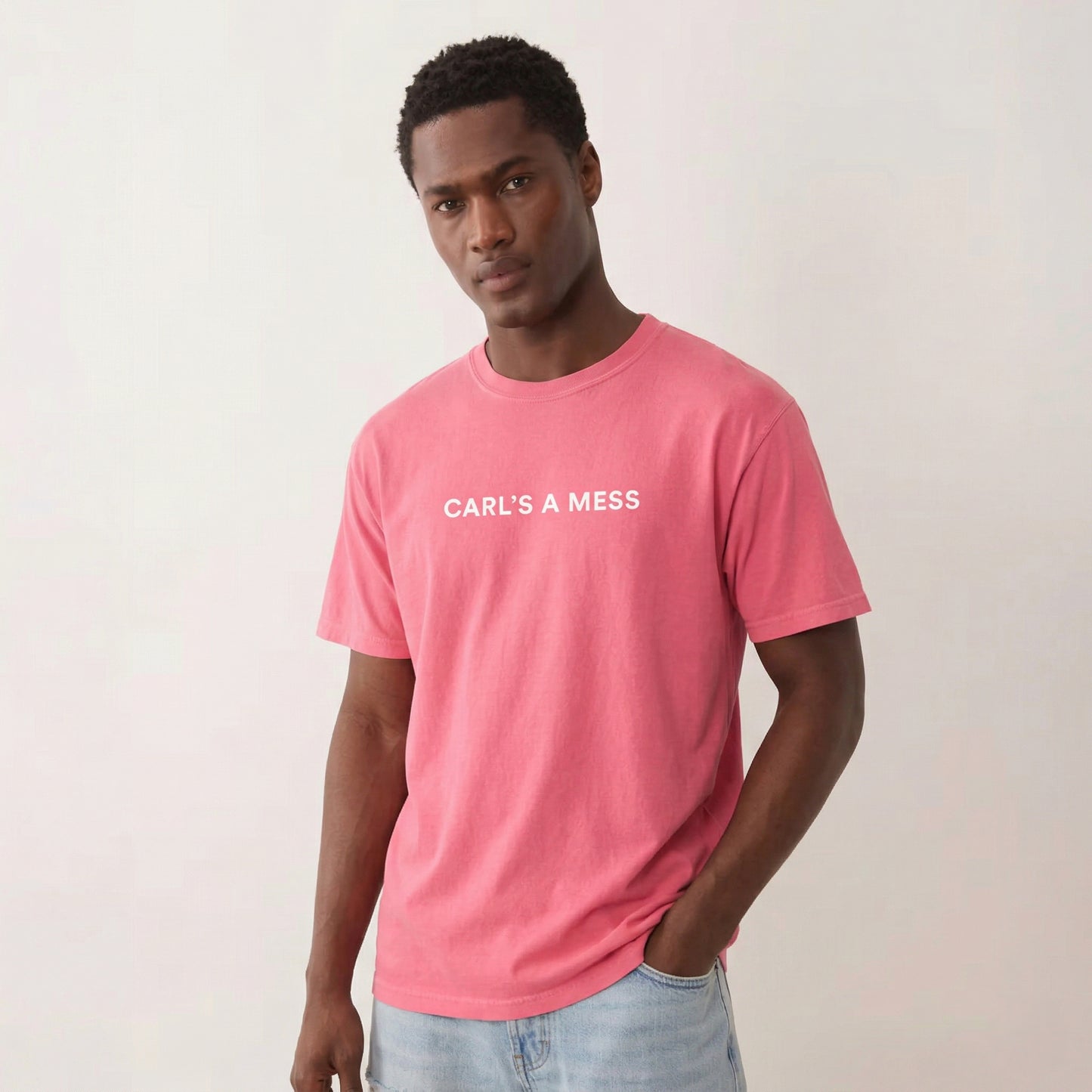 Man wearing a pink t-shirt with 'CARL'S A MESS' text on a plain background