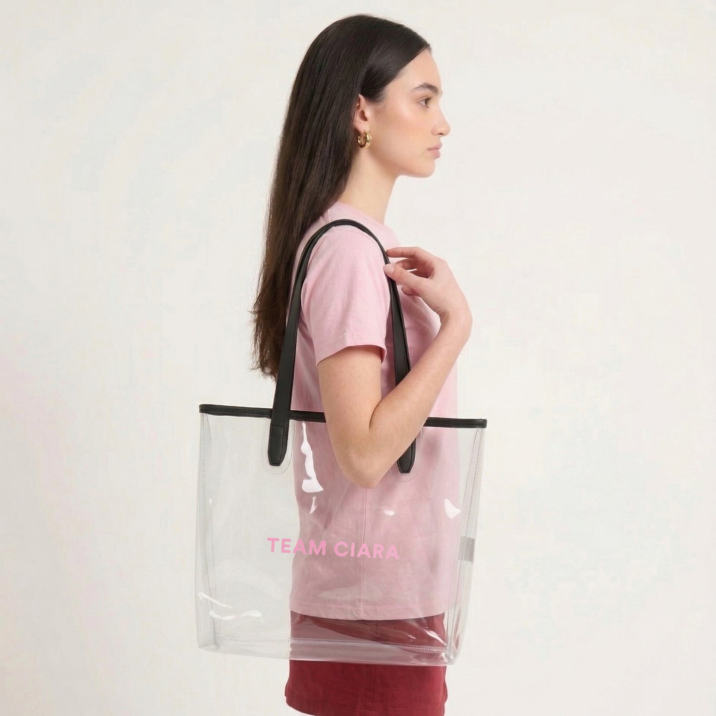 Woman carrying a clear tote bag with black straps and 'Team Ciara' text on a white background