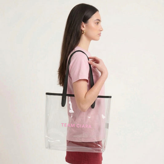 Woman carrying a clear tote bag with black straps and 'Team Ciara' text on a white background